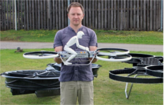 Chris MALLOY posant devant 2 versions de l'hoverbike, le drone dans les mains
